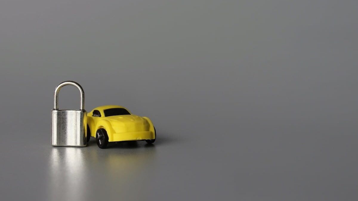 Car security, insurance and theft protection concept. Toy car and padlock. Copy space. Grey background
